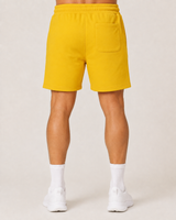 Model wearing the yellow AFLETE Core cotton shorts 018, shorts back view