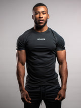 Man wearing a black AFLETE outfit with a logo on a gray background