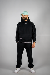 Model wearing the black AFLETE New Era tracksuit 001, full outfit front view