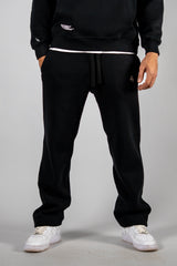 Model wearing the black AFLETE New Era tracksuit 001, joggers front view