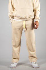 Model wearing the desert beige AFLETE New Era tracksuit 001, joggers front view