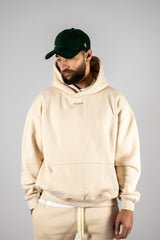 Model wearing the desert beige AFLETE New Era hoodie 002, hoodie front view