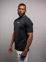 Model wearing the black AFLETE Essential Urban T-shirt 011, tshirt side view
