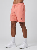 Model wearing the coral pink AFLETE Essential Urban shorts 012, shorts front view