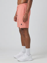 Model wearing the coral pink AFLETE Essential Urban shorts 012, shorts side view
