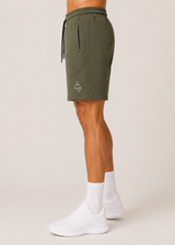 Model wearing the olive green AFLETE Core cotton shorts 018, shorts side view