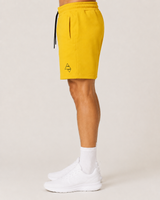 Model wearing the yellow AFLETE Core cotton shorts 018, shorts side view